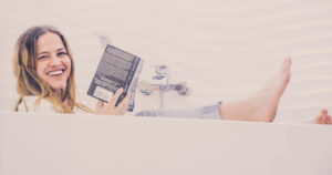 woman reading a book sitting, fully-clothed, in a bathtub
