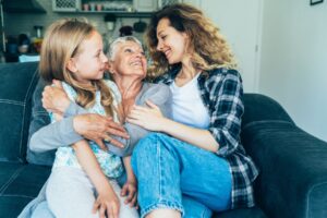 Grandmother, mother, daughter sitting on couch together