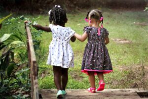 Two young girls of color walk hand in hand. Photo by Cheryl Holt on Pixabay