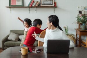 Young woman of Asian origin trying to work at home with active children